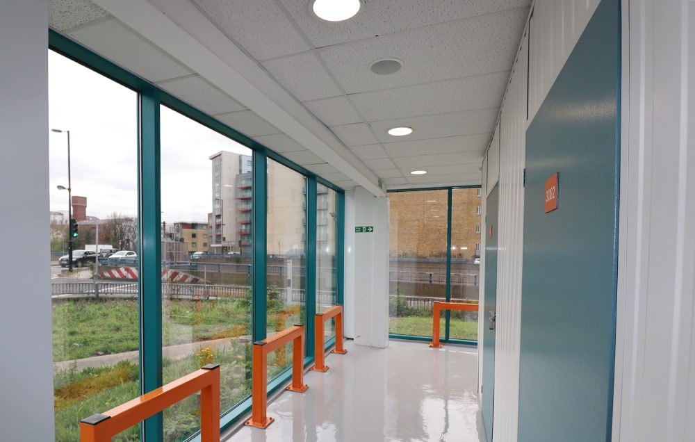 A bright hallway of a storage facility with large windows and a blue door.