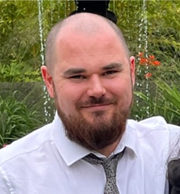 A selfie of a smiling man with a beard, wearing a dress shirt and tie.